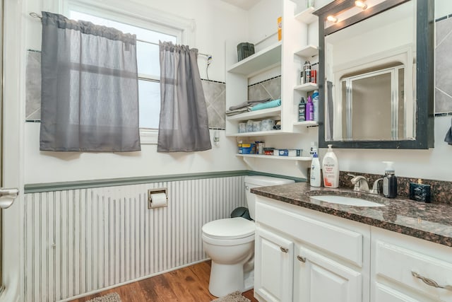 bathroom featuring hardwood / wood-style flooring, vanity, toilet, and a shower with shower door