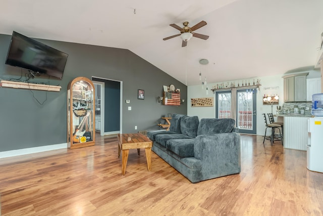 living room with ceiling fan, vaulted ceiling, and light wood-type flooring