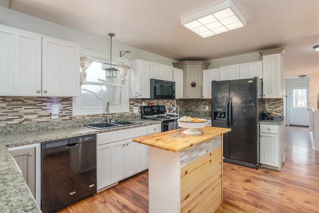 kitchen with sink, hanging light fixtures, a healthy amount of sunlight, and black appliances