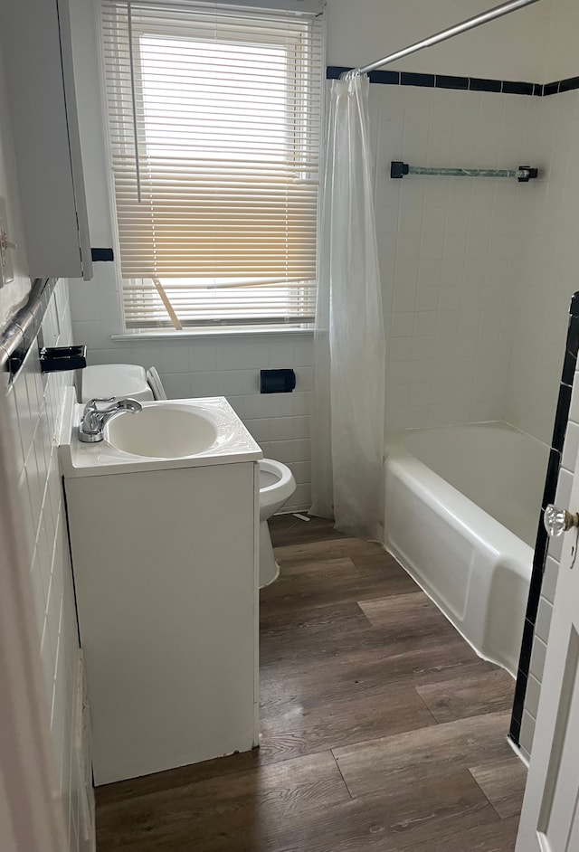 full bathroom featuring hardwood / wood-style flooring, toilet, a wealth of natural light, and tile walls