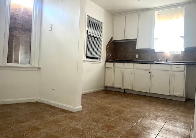 kitchen featuring white cabinets, backsplash, and sink