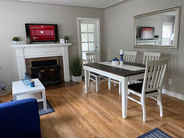 dining area with hardwood / wood-style floors, a fireplace, and a textured ceiling