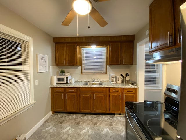 kitchen with electric range, sink, ceiling fan, and light stone countertops