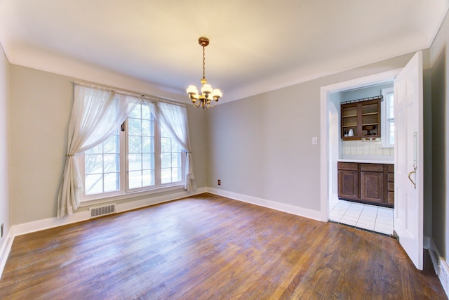 empty room with a chandelier and dark hardwood / wood-style floors