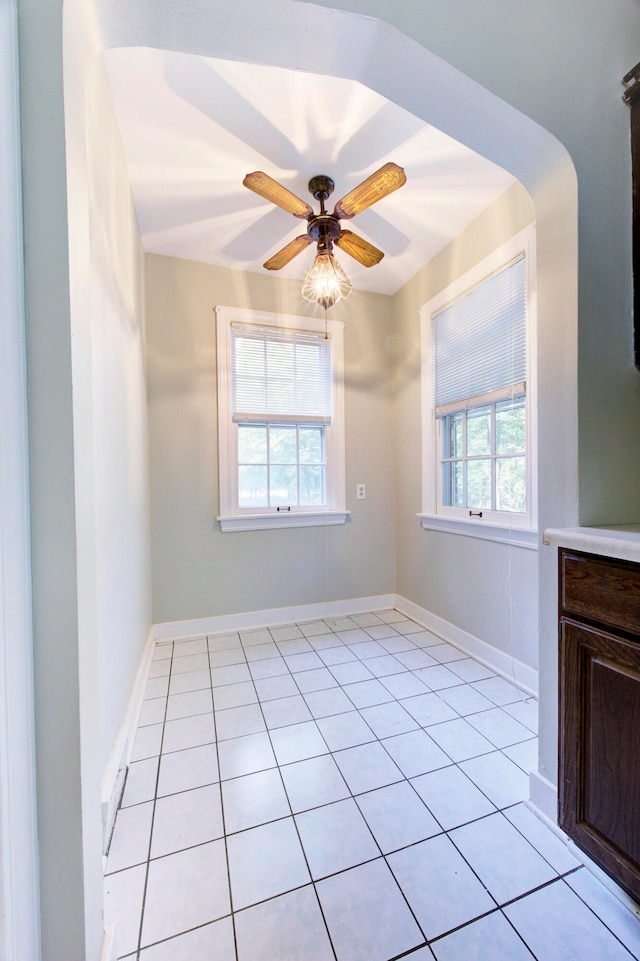 spare room featuring ceiling fan, a healthy amount of sunlight, and light tile patterned floors