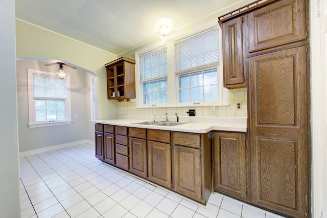 kitchen featuring decorative backsplash, ceiling fan, light tile patterned floors, and sink