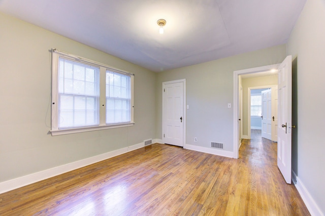 unfurnished bedroom with light hardwood / wood-style flooring and multiple windows