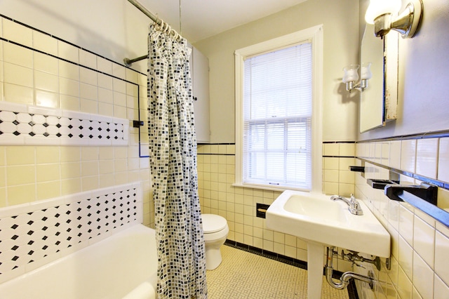 bathroom with shower / bath combo with shower curtain, tile patterned floors, tile walls, and a healthy amount of sunlight