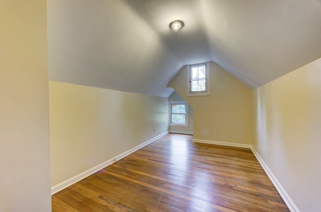 additional living space with hardwood / wood-style floors and vaulted ceiling