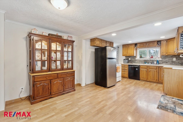 kitchen with black dishwasher, tasteful backsplash, stainless steel fridge, light wood-type flooring, and ornamental molding