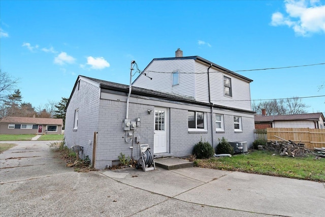 rear view of property with a lawn and cooling unit