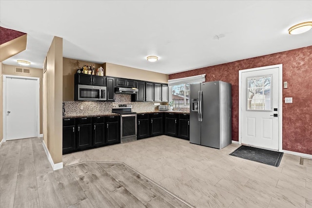 kitchen with backsplash, stainless steel appliances, and light hardwood / wood-style flooring