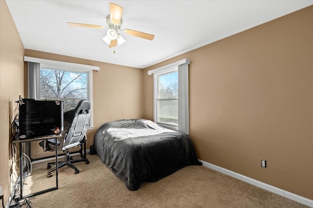 bedroom featuring ceiling fan, light colored carpet, and multiple windows