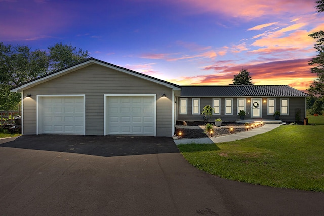 single story home featuring a garage and a yard