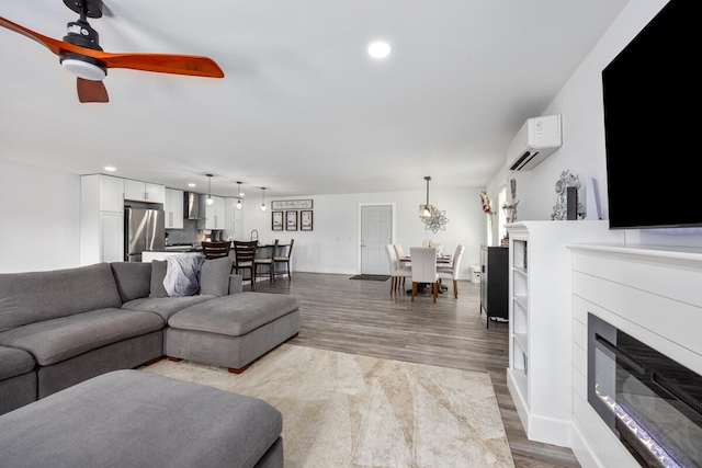 living room with hardwood / wood-style flooring, ceiling fan, and a wall mounted air conditioner