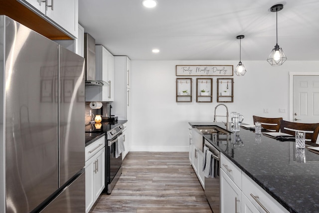 kitchen with white cabinetry, wall chimney range hood, and appliances with stainless steel finishes