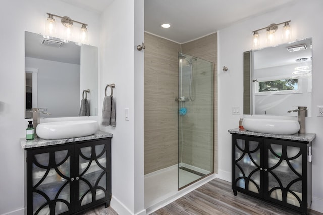 bathroom featuring wood-type flooring, vanity, and a tile shower