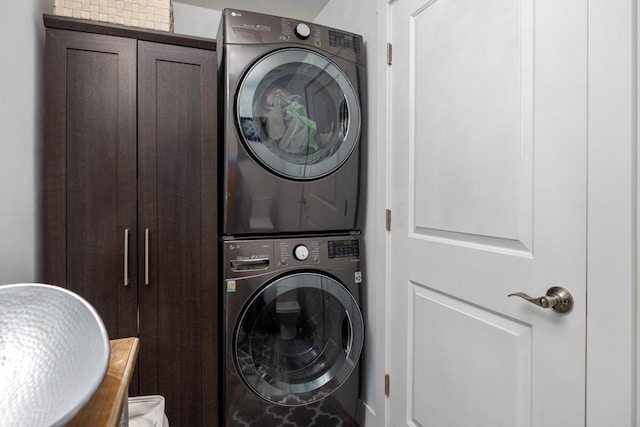 laundry area with cabinets and stacked washer / drying machine