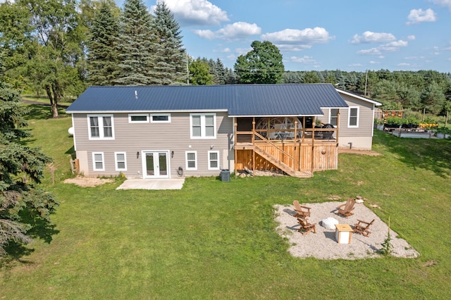 back of property featuring a fire pit, a yard, a wooden deck, a patio area, and french doors