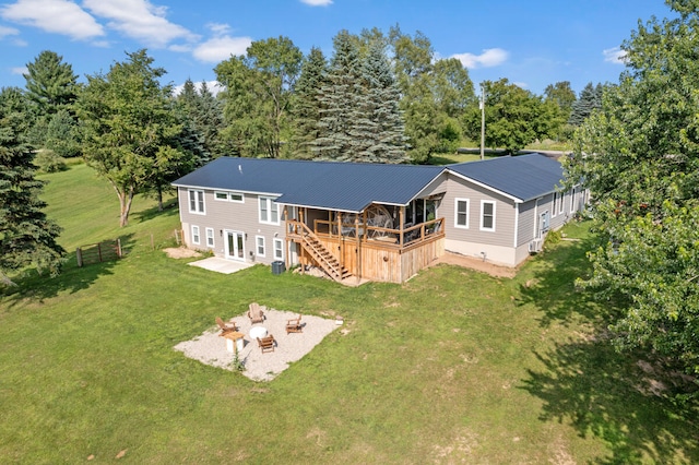 rear view of property featuring a fire pit, a lawn, a deck, and a patio area