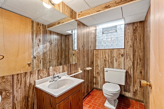 bathroom with wooden walls and a drop ceiling