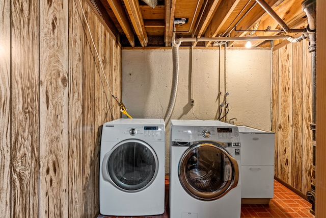 laundry area with separate washer and dryer and wood walls