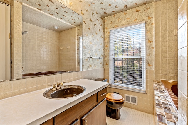 bathroom with vanity, a bathtub, toilet, and tile walls