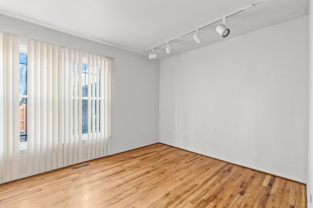 empty room with light hardwood / wood-style flooring and track lighting