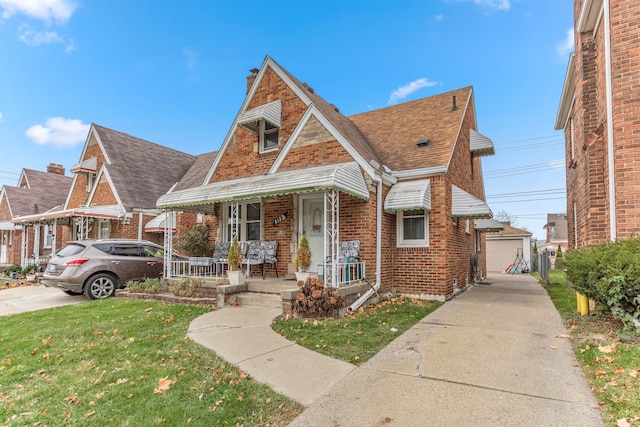 view of front of house featuring a garage, covered porch, an outdoor structure, and a front lawn