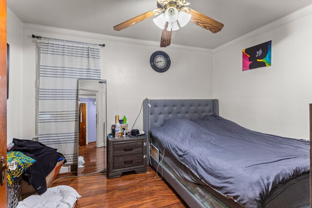 bedroom with ceiling fan, crown molding, and dark wood-type flooring