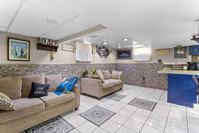 living room with a drop ceiling and light tile patterned flooring