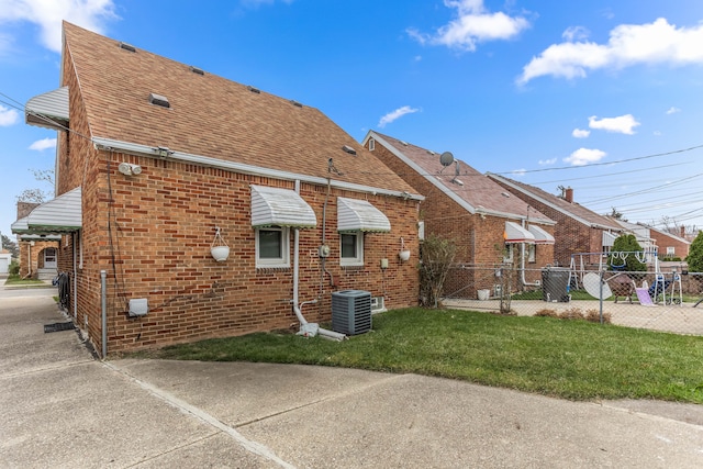 rear view of property with central air condition unit and a yard