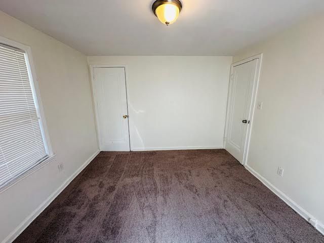 spare room featuring dark colored carpet