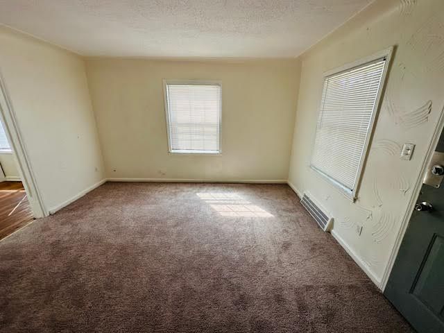 unfurnished room featuring dark carpet and a textured ceiling