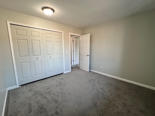 unfurnished bedroom featuring dark colored carpet and a closet