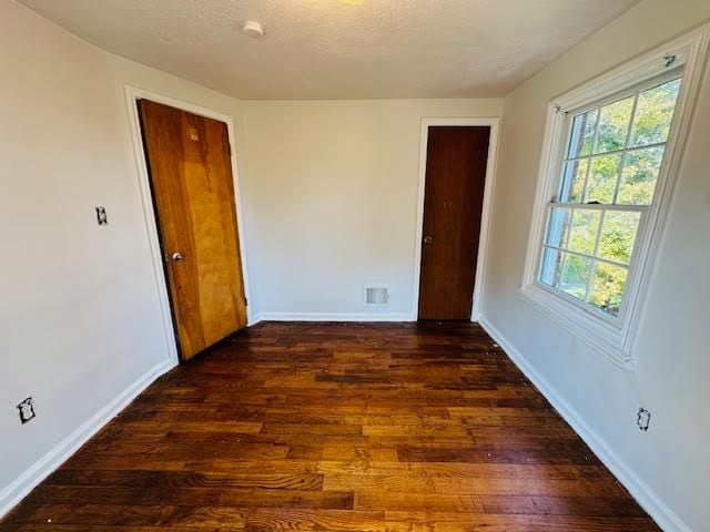 spare room featuring a textured ceiling and dark wood-type flooring