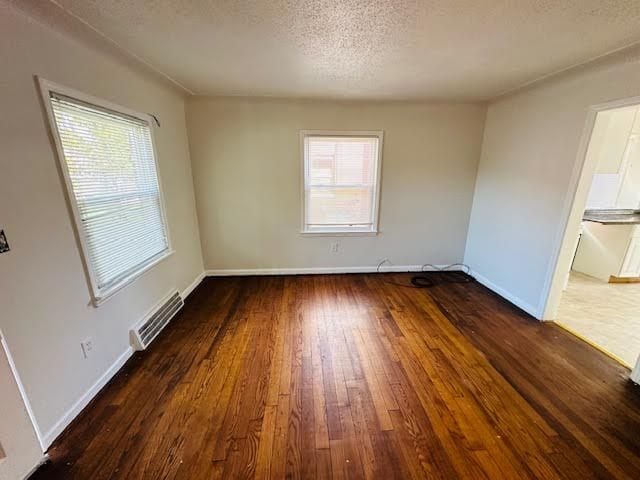 spare room featuring dark hardwood / wood-style flooring and a textured ceiling