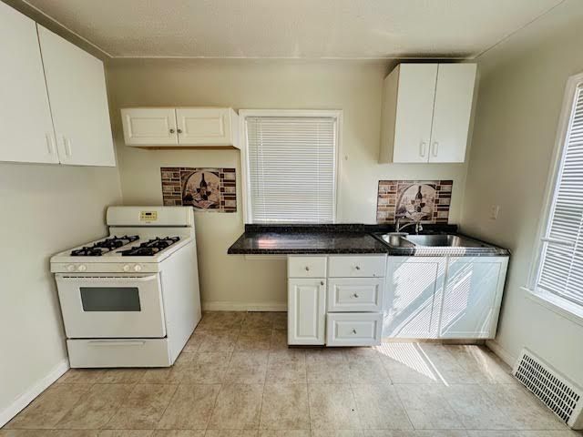 kitchen featuring white cabinetry, sink, and white range with gas stovetop