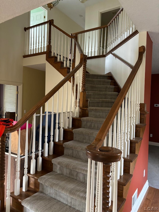 stairs with high vaulted ceiling and wood-type flooring