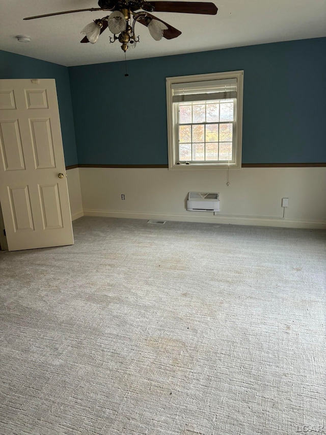 unfurnished room with light colored carpet, an AC wall unit, and ceiling fan