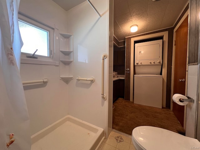 bathroom with walk in shower, a textured ceiling, stacked washer and clothes dryer, tile patterned flooring, and toilet