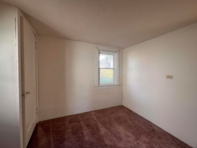 carpeted empty room featuring a textured ceiling