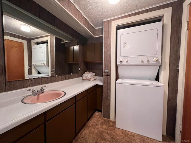 interior space featuring a textured ceiling, wooden walls, vanity, and stacked washer / drying machine