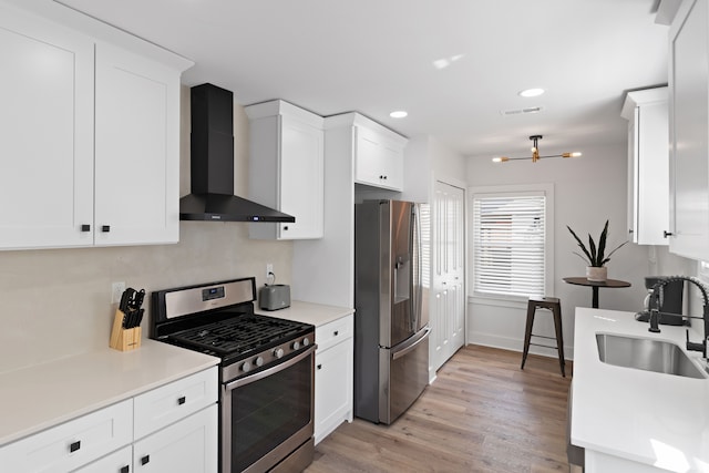 kitchen featuring sink, white cabinets, wall chimney range hood, and appliances with stainless steel finishes