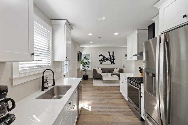 kitchen featuring appliances with stainless steel finishes, light hardwood / wood-style floors, white cabinetry, and sink