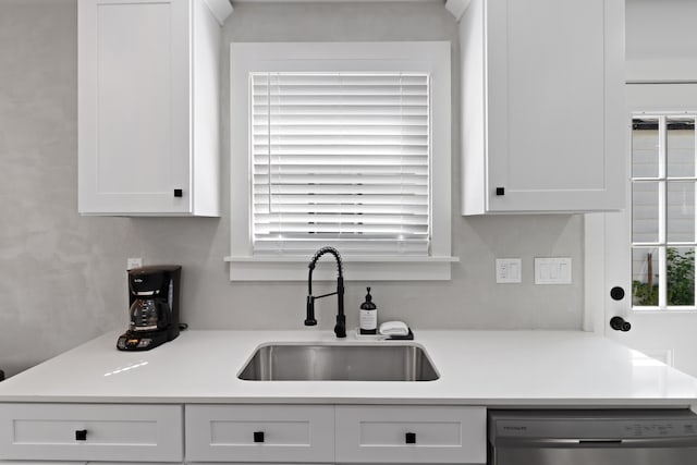 kitchen with dishwasher, white cabinetry, and sink