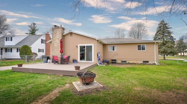 rear view of property with a lawn, a deck, and an outdoor fire pit