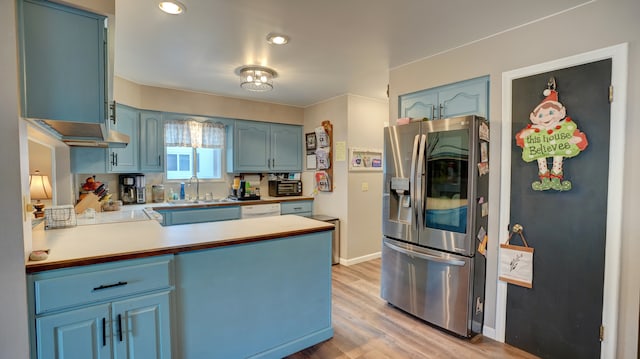 kitchen featuring sink, light hardwood / wood-style flooring, stainless steel fridge, blue cabinetry, and kitchen peninsula