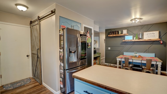 kitchen featuring stainless steel fridge with ice dispenser, a barn door, and wood-type flooring