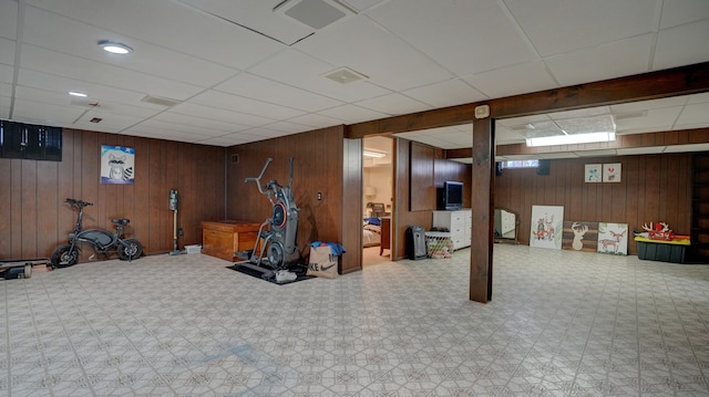 exercise room with wooden walls and a drop ceiling